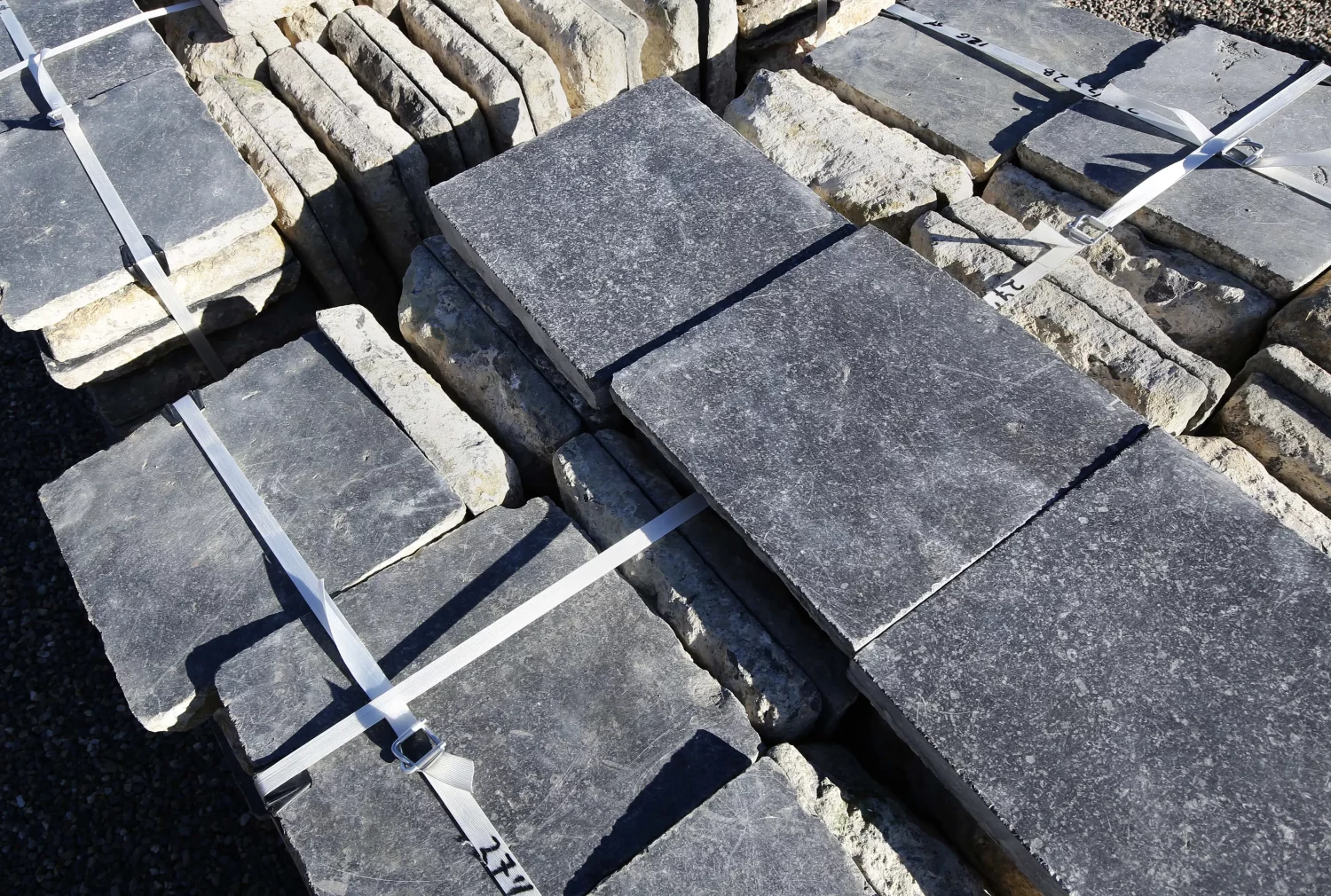 Limited batch of reclaimed Noir de Mazy 47x47 cm church tiles stacked on pallets at De Opkamer