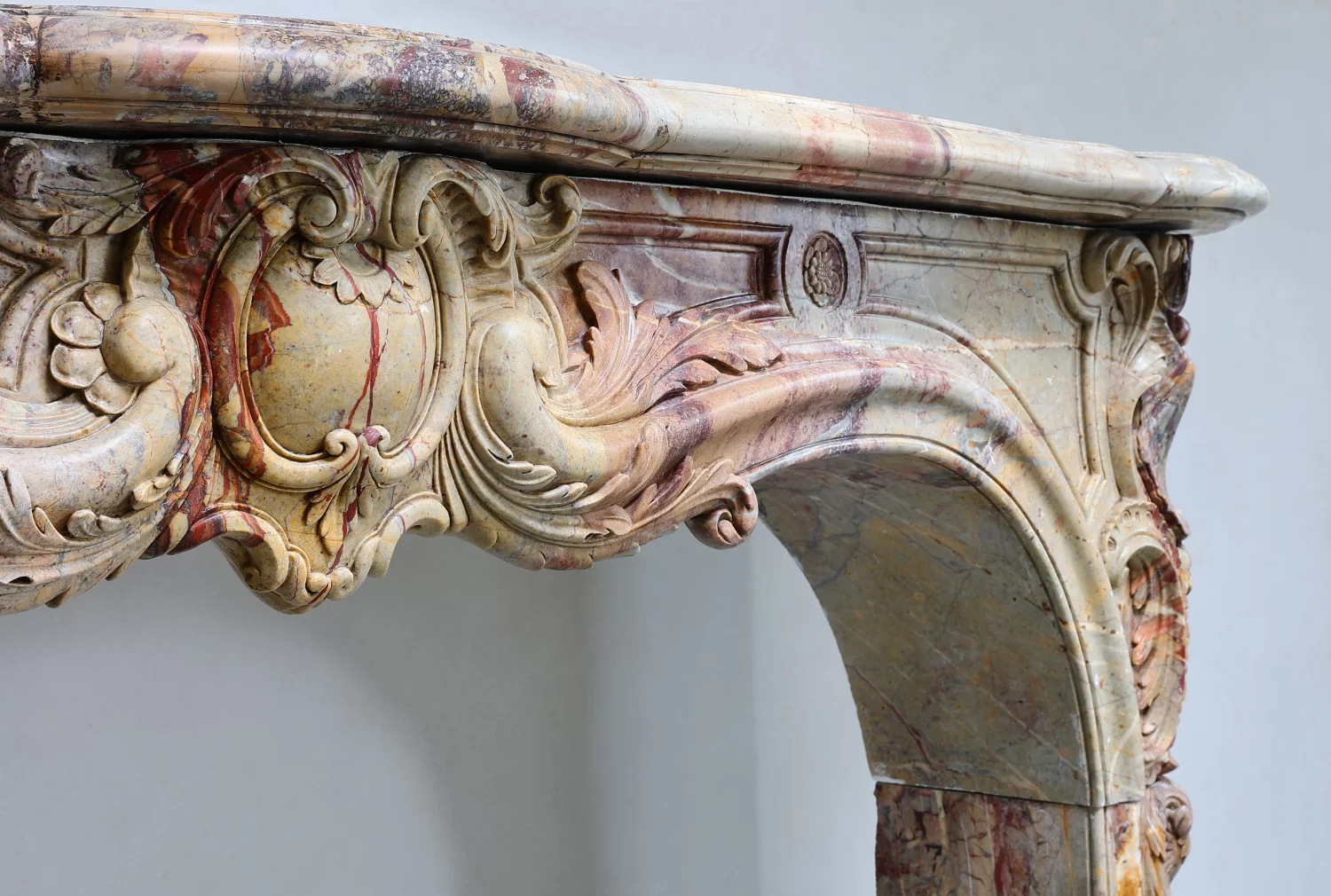 Detail of antique Sarrancolin marble Fireplace Mantel from Paris, Louis XV arched opening, shell motif, floral rosette, acanthus carving and warm polychrome veining