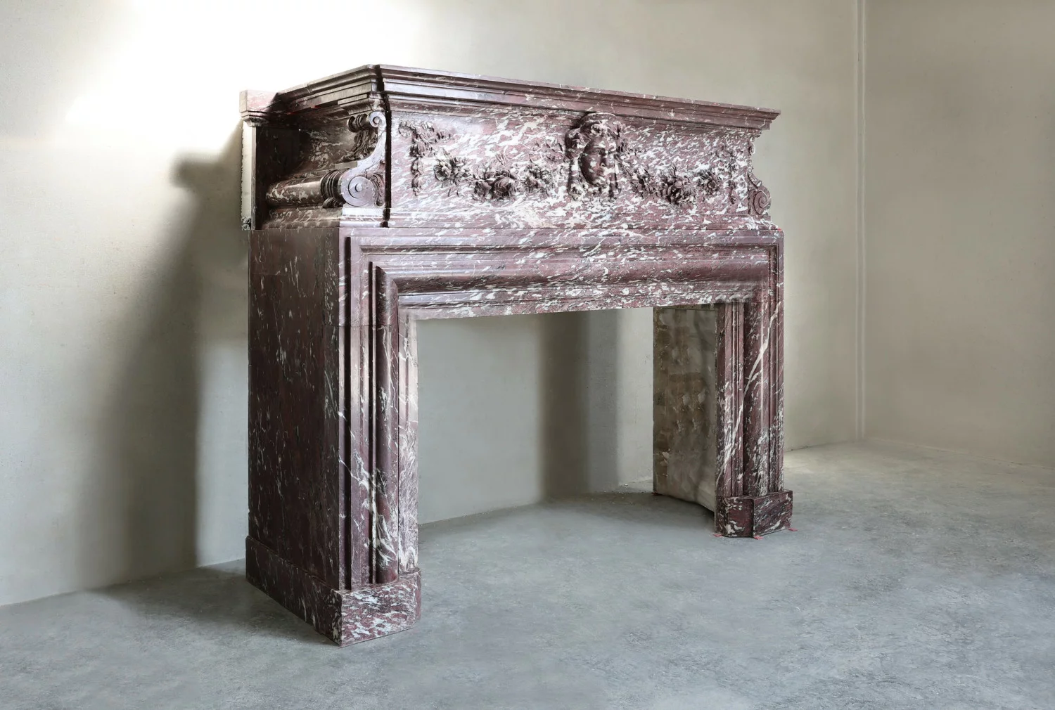 Angled view of antique marble chimneypiece in Fleur de Pêcher marble with visible patina and timeworn finish