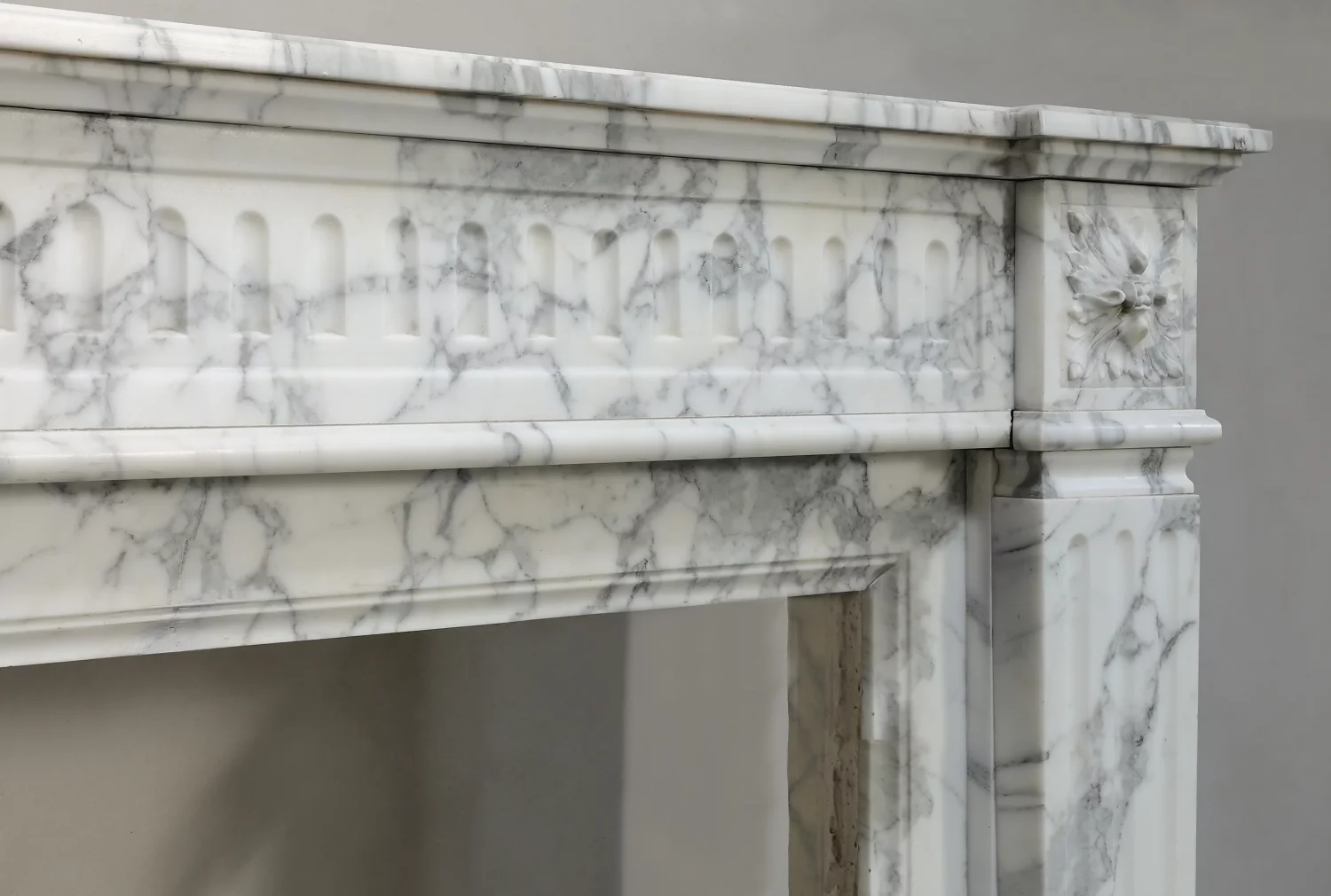 Detail of the fluted Arabescato marble frieze, right corner rosette and moulded edge above the opening