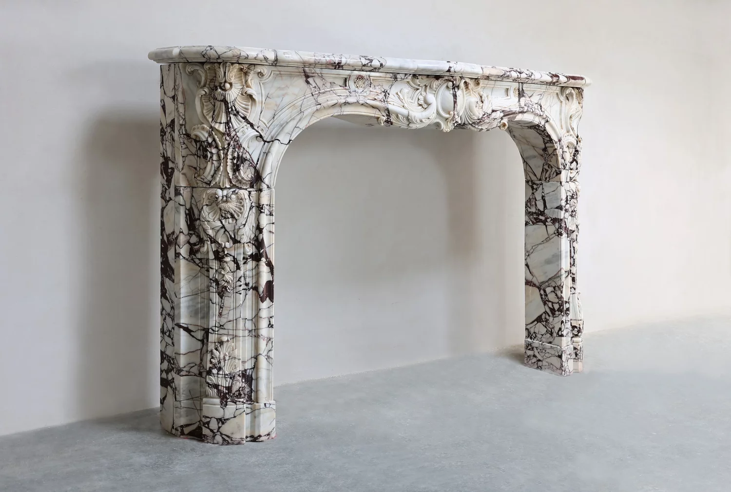 Angled view of antique Louis XV marble Fireplace Mantel in rare Breche Violetta, 19th century Parisian vintage mantle with carved Rococo details