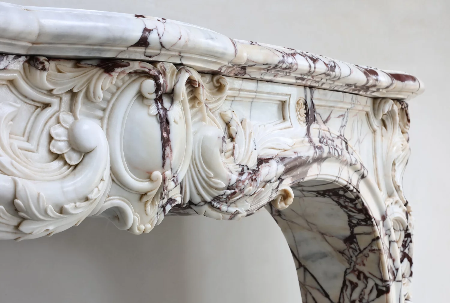 Detail of rare Breche Violetta marble antique Fireplace Mantel, carved Louis XV arch, floral ornament and dramatic violet brown veining from Paris France
