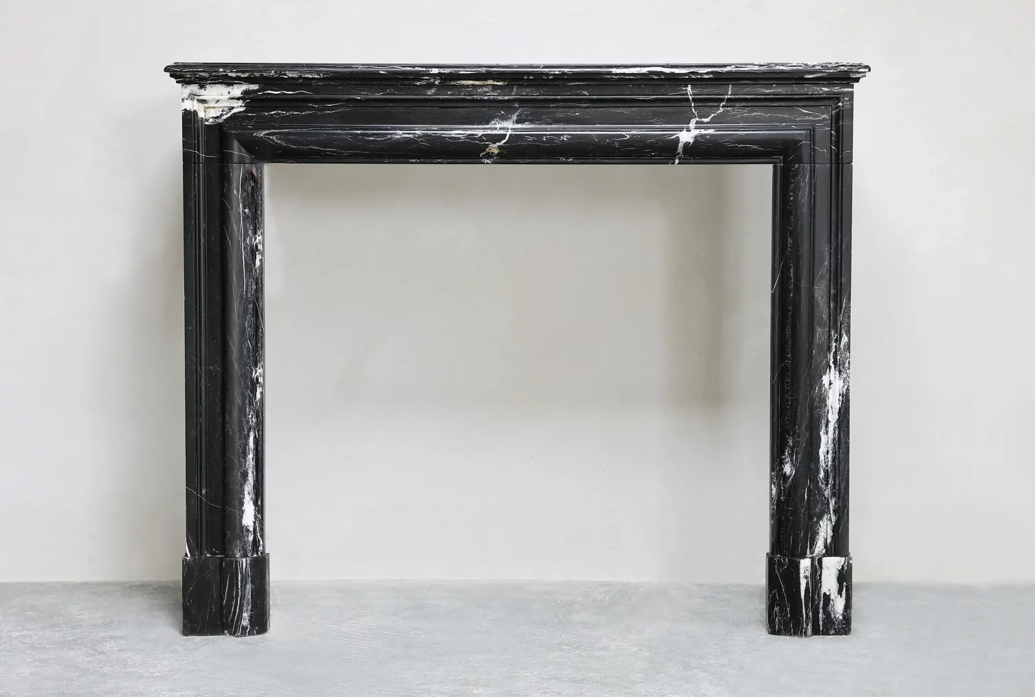 Front view of an antique Nero Marquina marble mantelpiece with white veining and rounded Boudin mouldings.