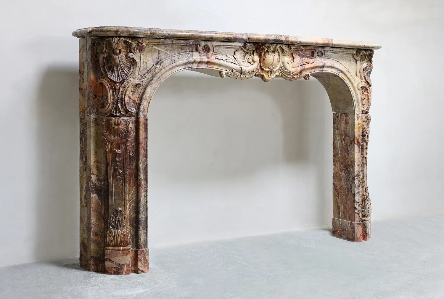Angled view of antique French Louis XV Fireplace Mantel in Sarrancolin marble, professionally restored 19th century Parisian mantle with carved Rococo ornamentation
